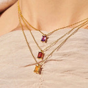 Three layered gold-tone necklaces with purple, red and amber rectangular pendants