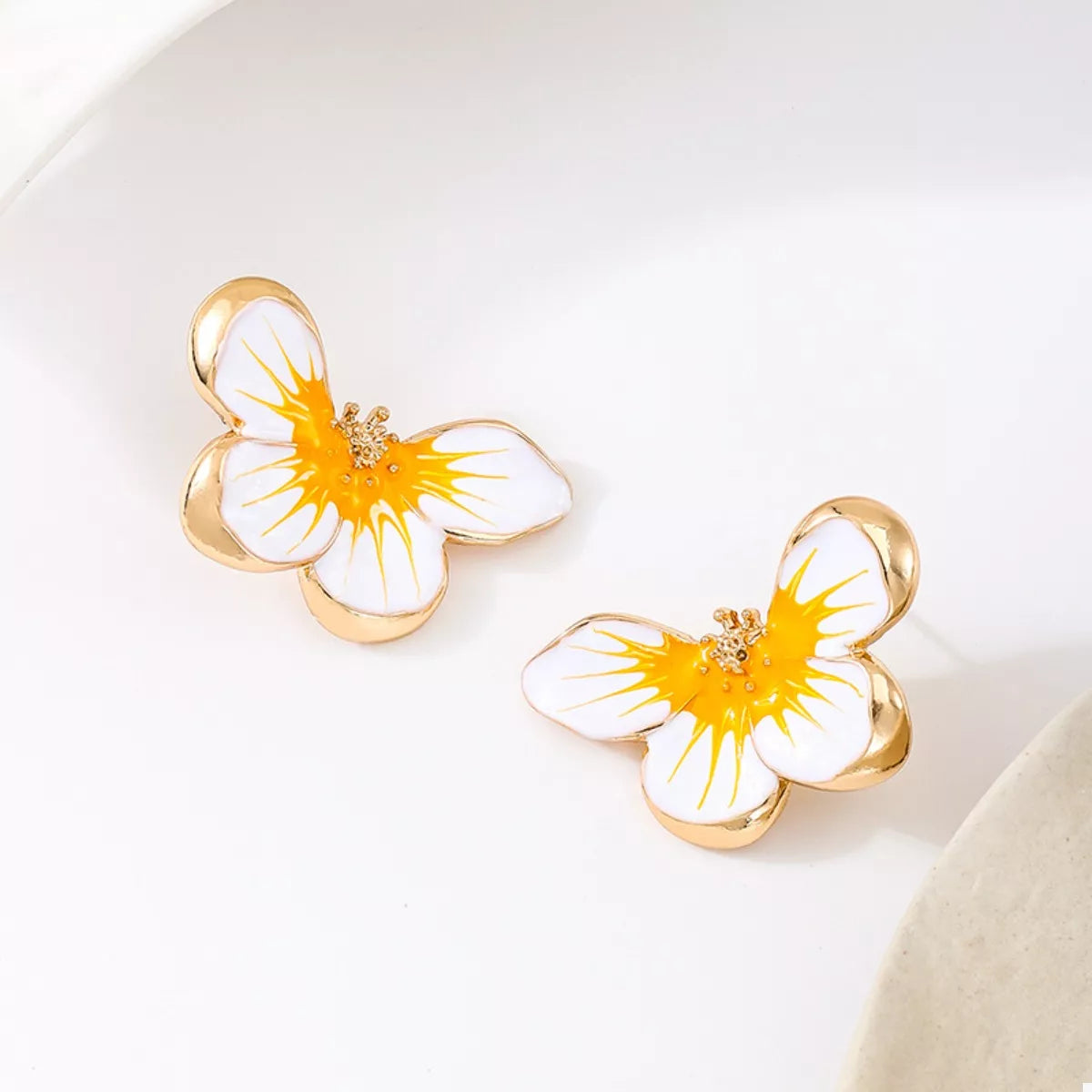 Pair of yellow-and-white flower studs viewed at an angle