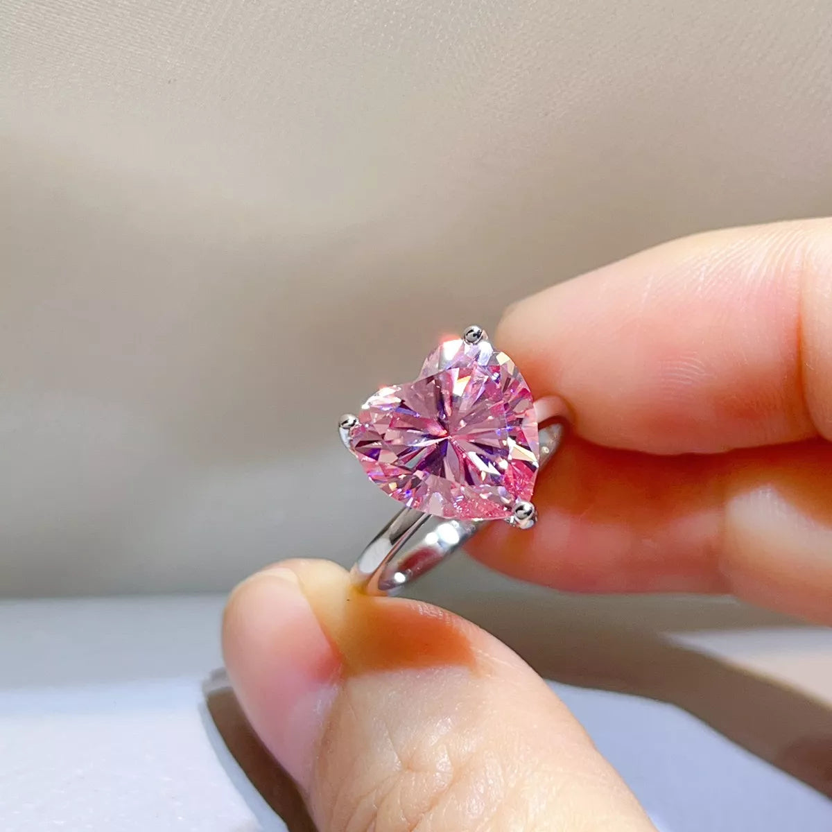 Close-up of the pink heart centre stone held between fingers.