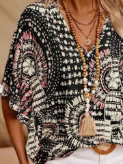 Black-and-white printed half-sleeve blouse on a model holding one side of the fabric outward.