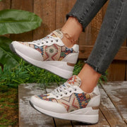Side view of cream patterned wedge sneakers showing white wedge soles and floral side panels