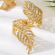 Gold-tone leaf cuff bracelet displayed upright on white surface