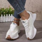 Pair of white sneakers with black side stripes worn with jeans