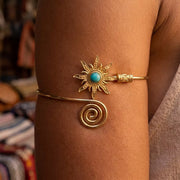 Gold-tone sunburst cuff bracelet with turquoise center shown on a wrist