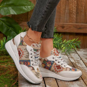 Pair of cream lace-up wedge sneakers with multicolor geometric floral panels, worn with dark jeans