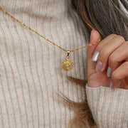 Close view of gold-tone sunburst evil eye necklace pendant
