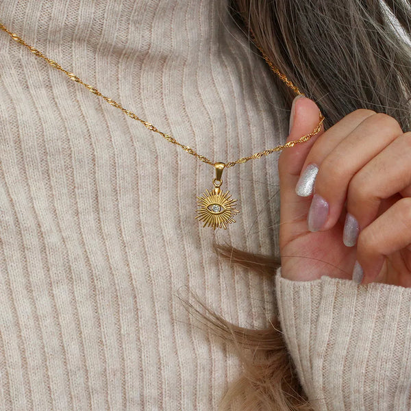 Close view of gold-tone sunburst evil eye necklace pendant