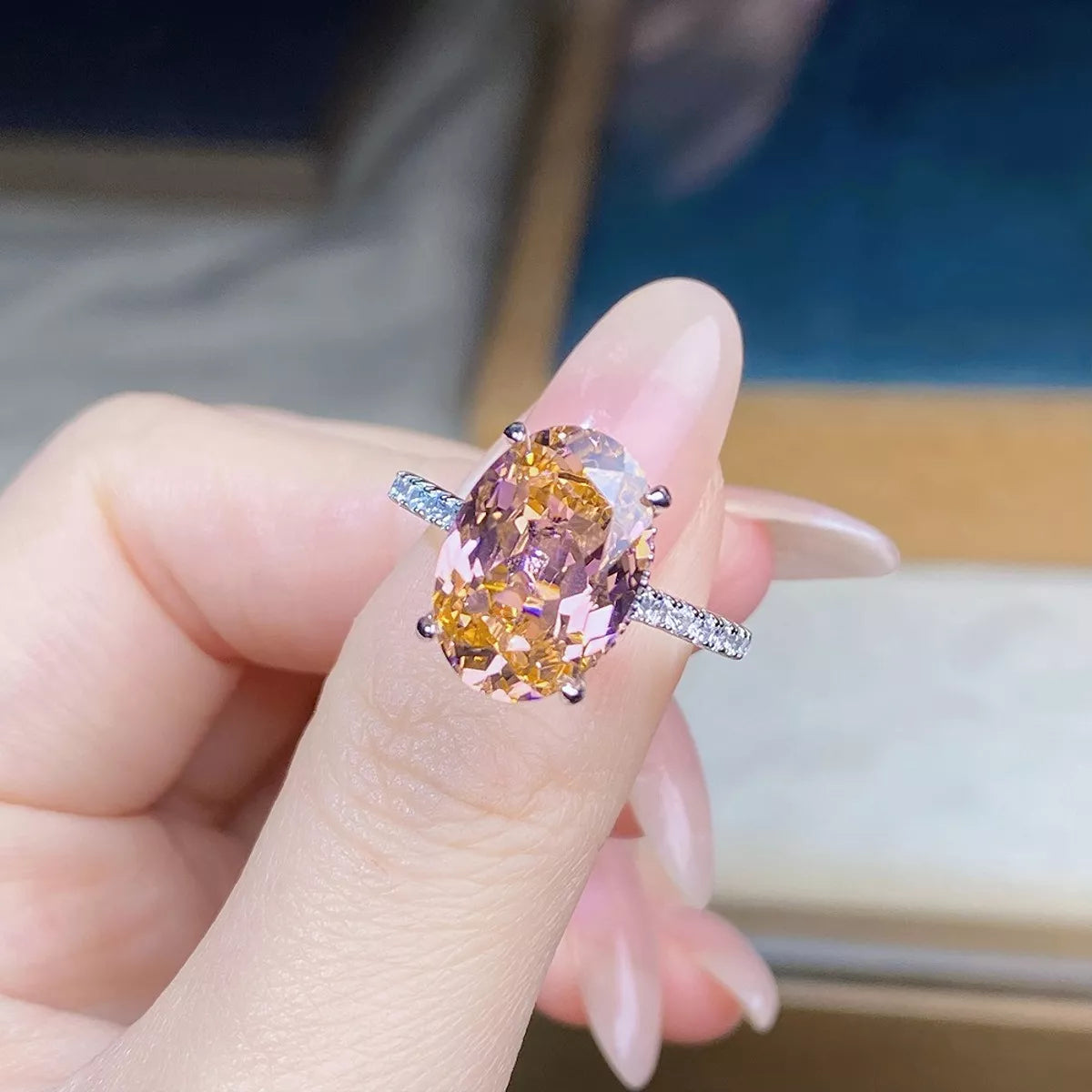 Close-up of the pink oval center stone and clear-stone shoulders on the ring