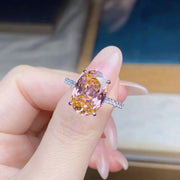 Close-up of the pink oval center stone and clear-stone shoulders on the ring
