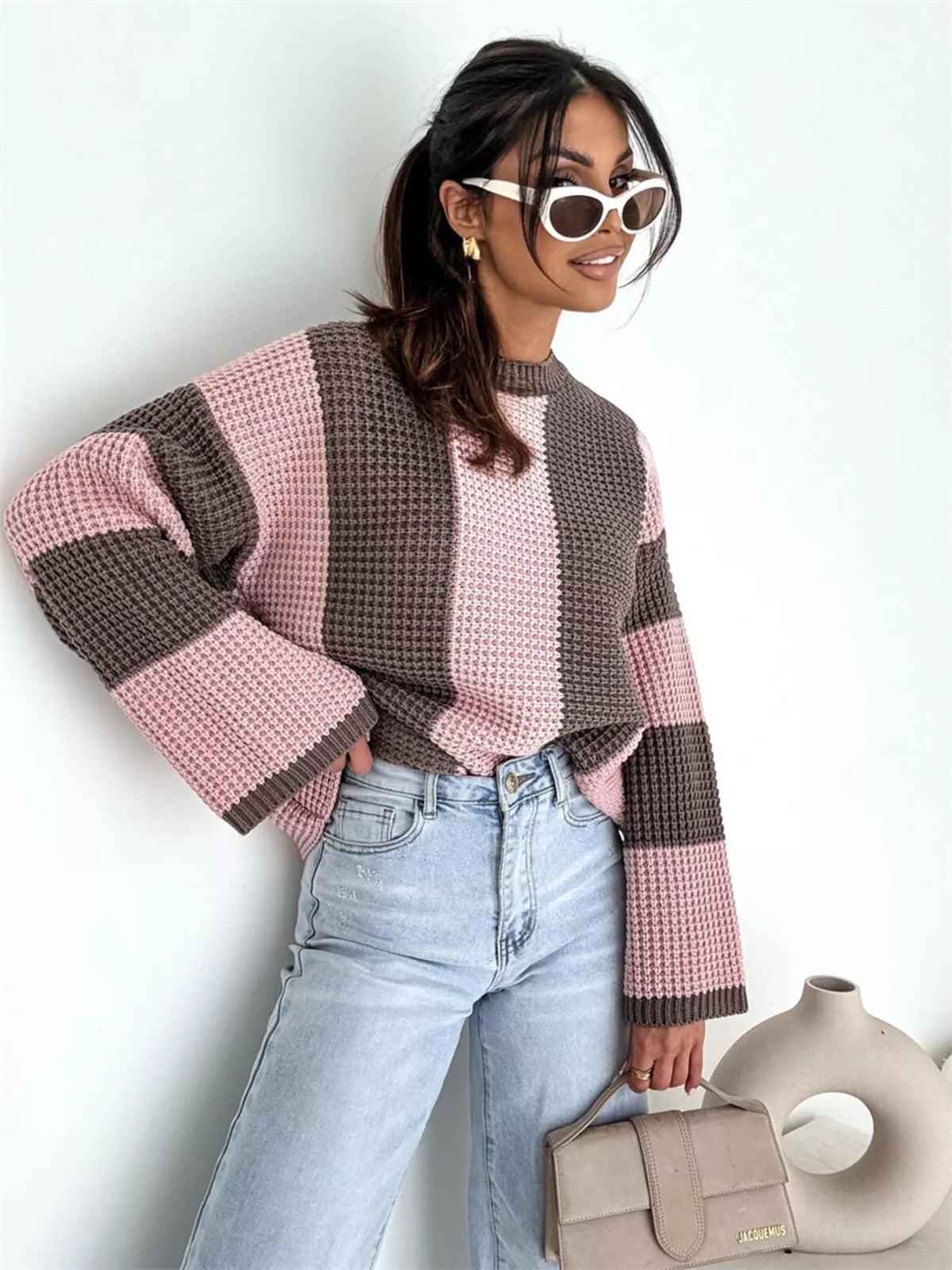 Model standing in pink and brown oversized sweater with wide sleeves