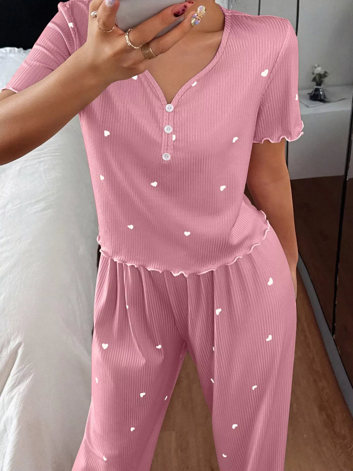 Close view of pink heart-print top with buttoned neckline and lettuce trim