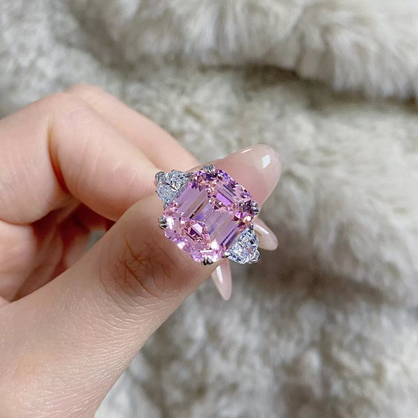 Close-up of a blush pink rectangular zircon ring held between fingers
