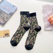 Pair of dark sheer crew socks with floral pattern, black cuffs and toes