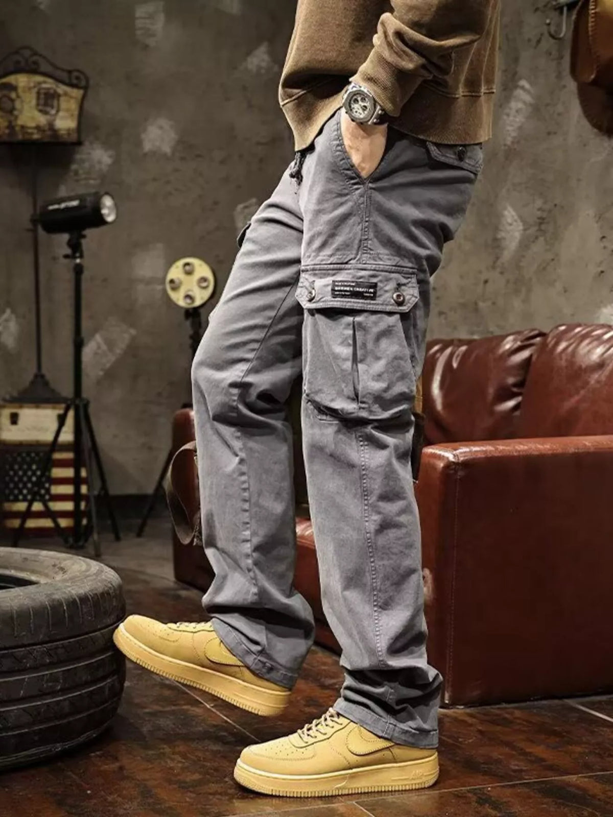 Angled close view of gray cargo pants highlighting the buttoned thigh-pocket flap.