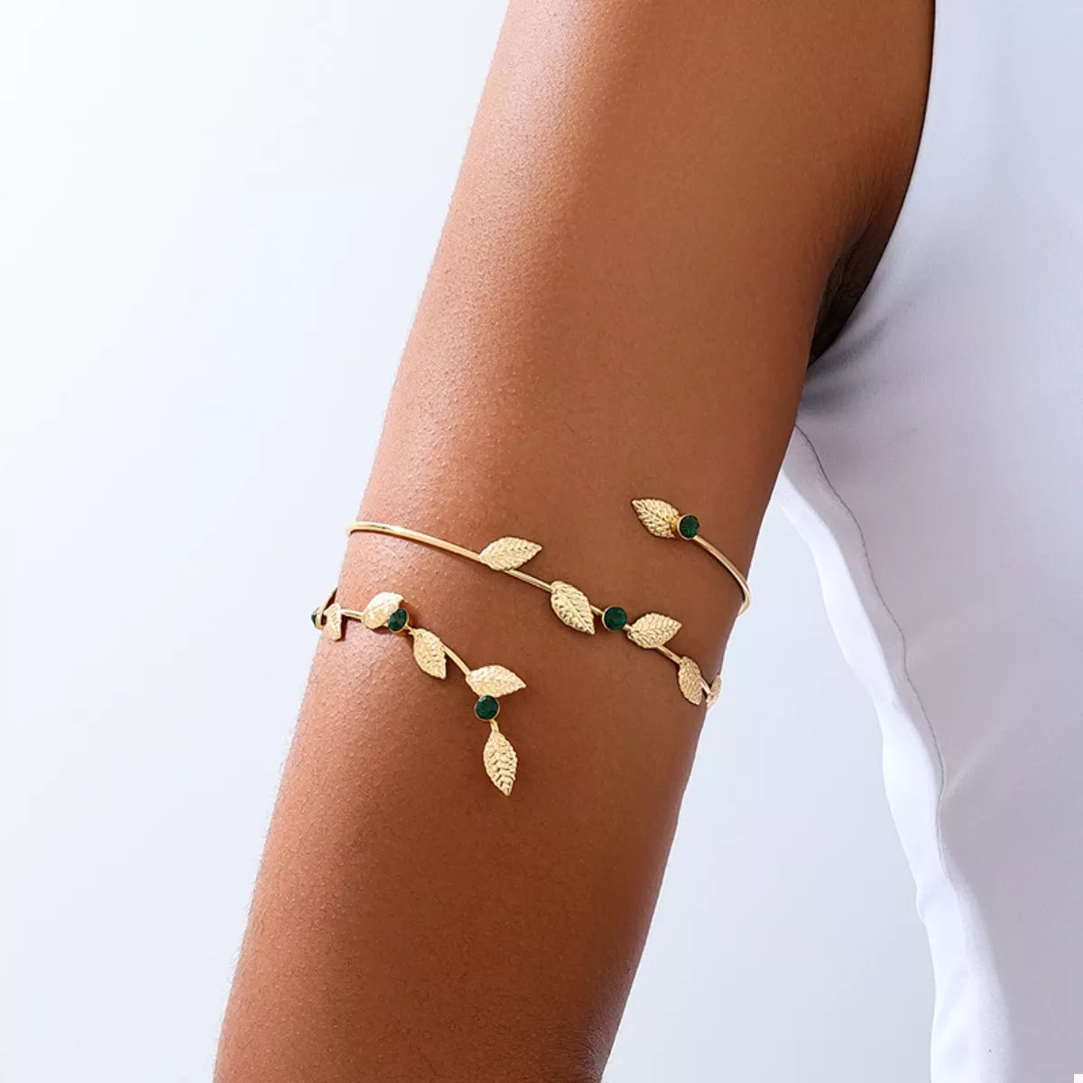 Gold-tone leaf bracelet with green accents worn on wrist