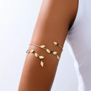 Gold-tone leaf bracelet with green accents worn on wrist