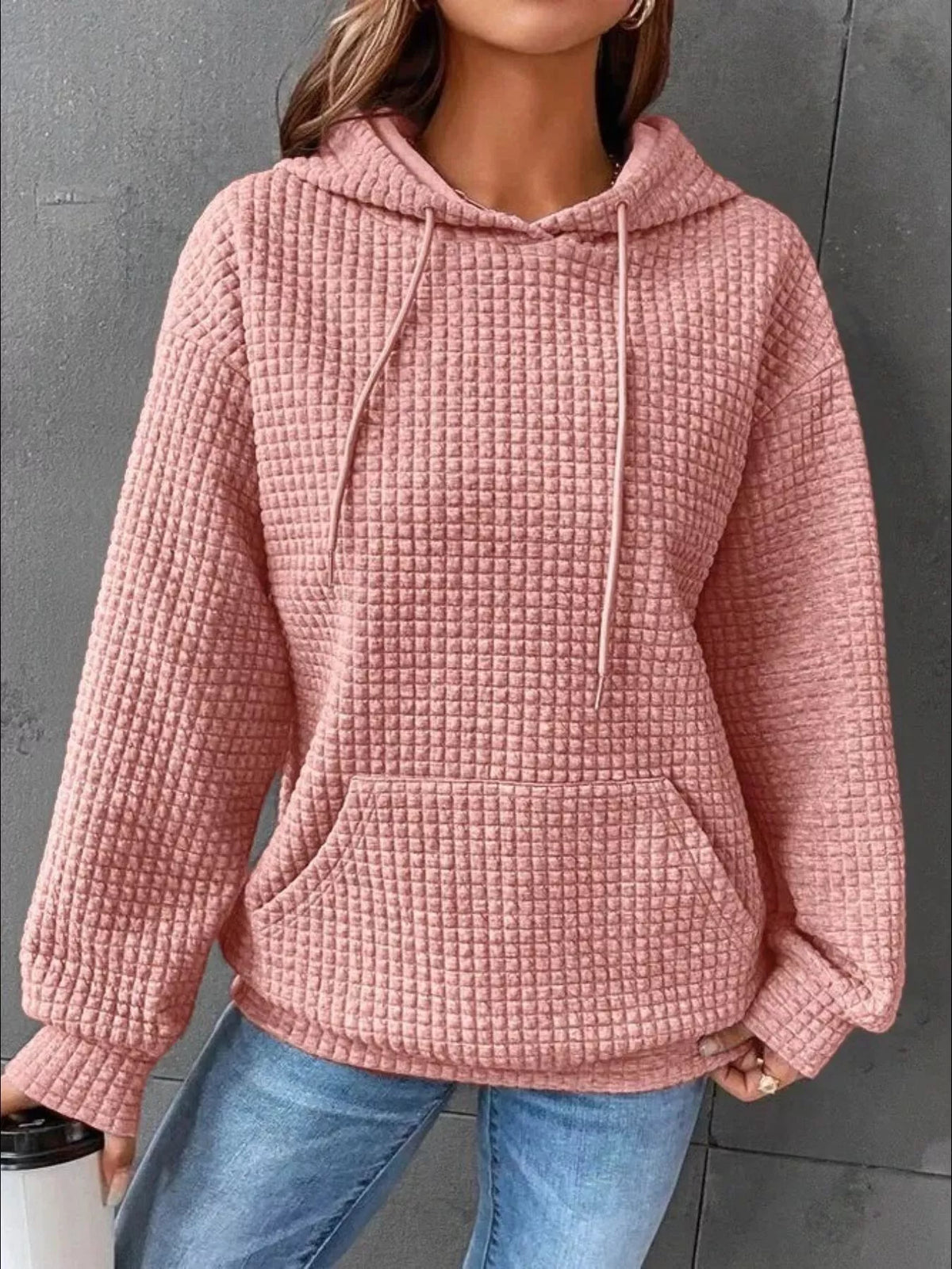 Front view of pink textured hoodie worn with jeans