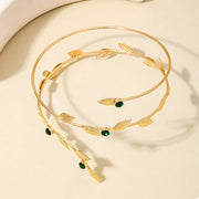 Gold-tone leaf bracelet with green accent stones on light surface