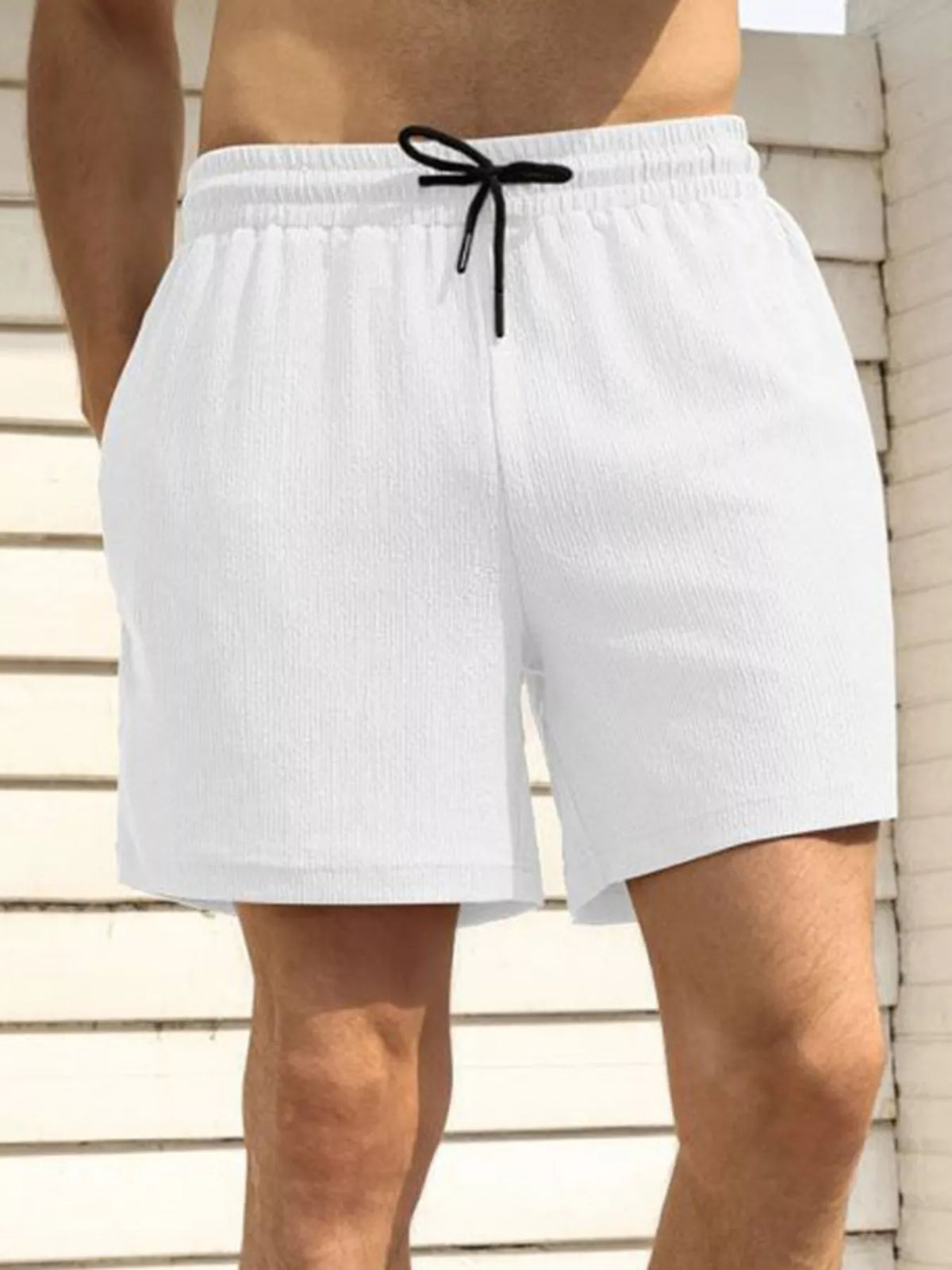 Model wearing white drawstring shorts, front view with hands in pockets