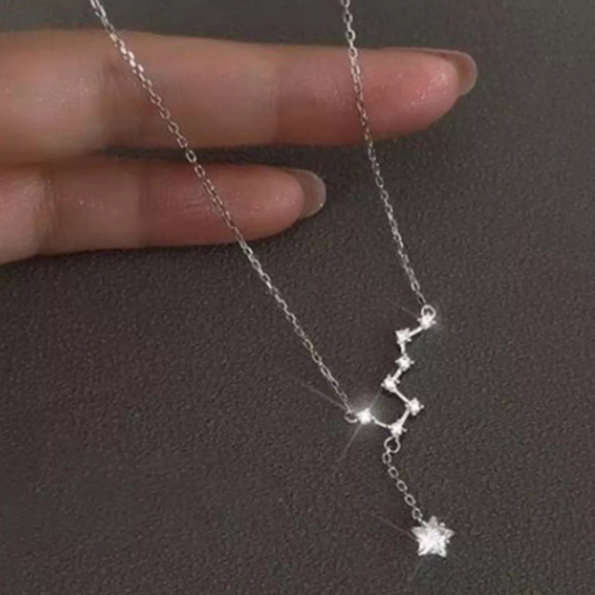 Hand holding silver chain with star-shaped charms