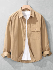 Tan long-sleeve men's button-up shirt layered open over a white T-shirt, with a buttoned chest pocket