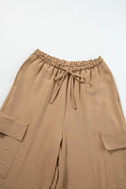 Close view of tan trousers showing the gathered drawstring waist and cargo pockets