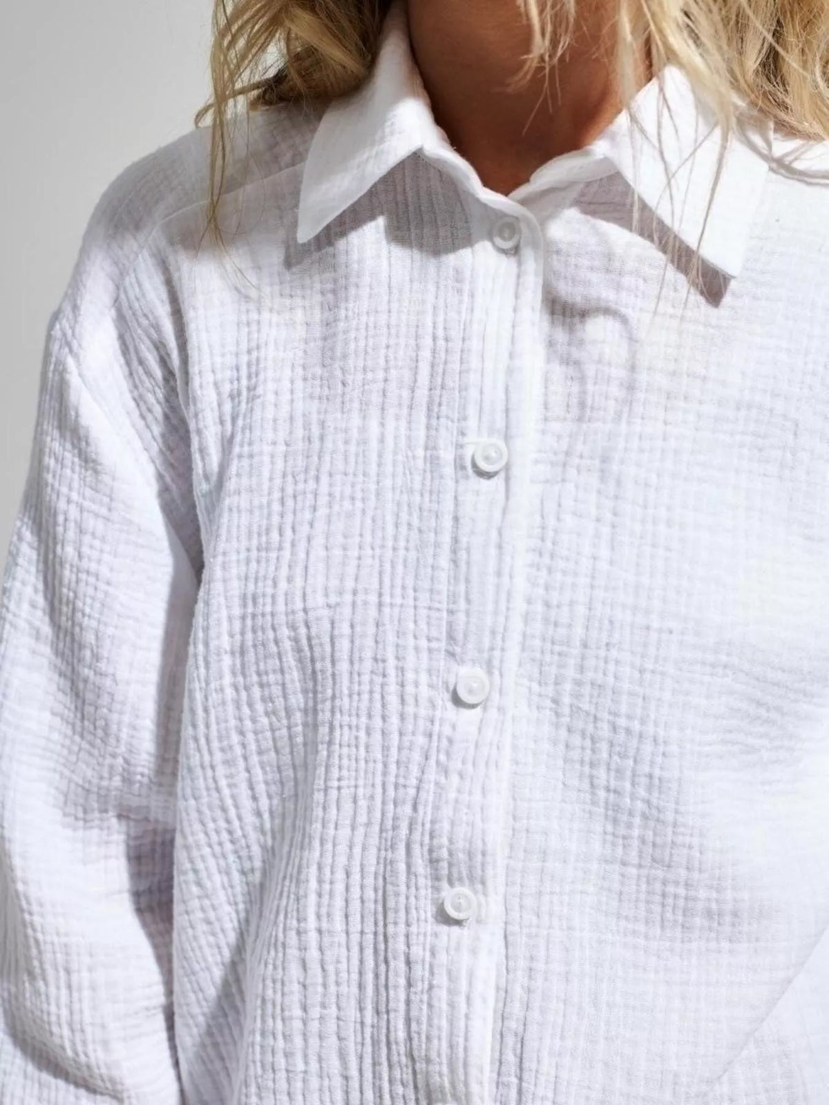 Close front view of white gauze shirt showing buttons and textured fabric.