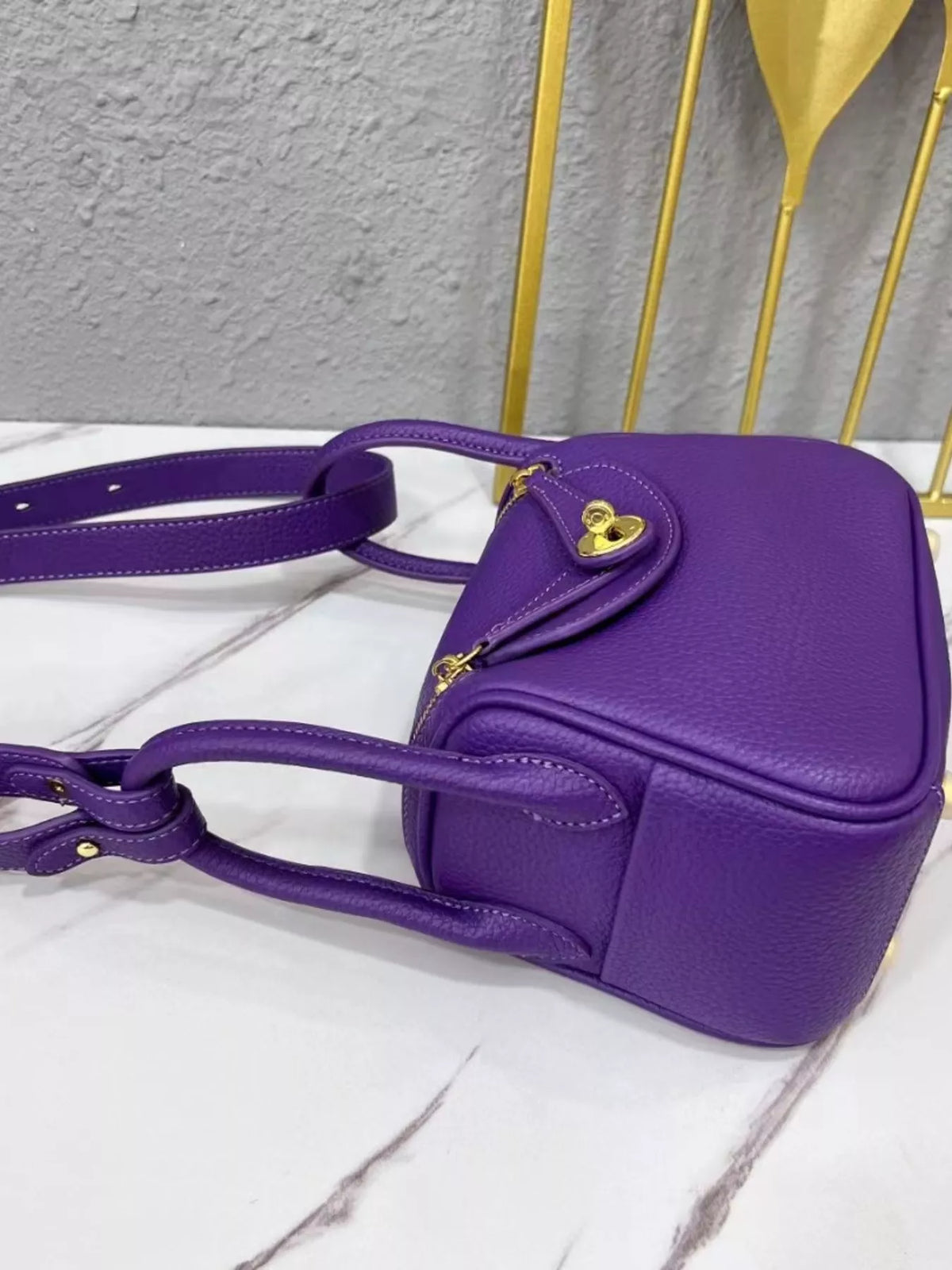 Side view of the purple crossbody bag showing its base