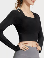 Close angled view of black active top showing the sheer sleeve and fitted cropped hem