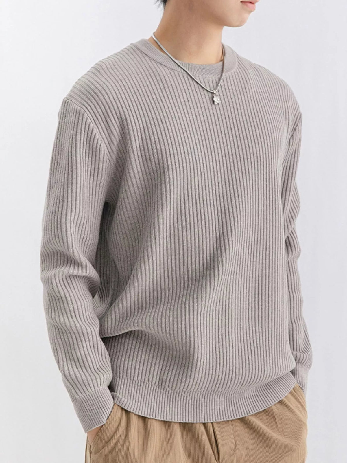 Side-angled view of taupe ribbed sweater with a hand in a trouser pocket