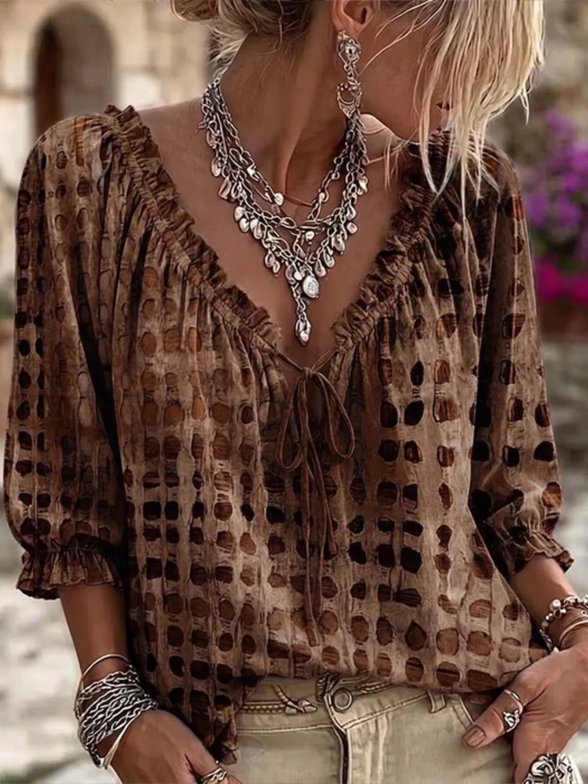 Brown geometric-print ruffle-neck blouse worn with beige jeans.