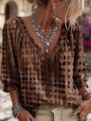 Brown geometric-print ruffle-neck blouse worn with beige jeans.