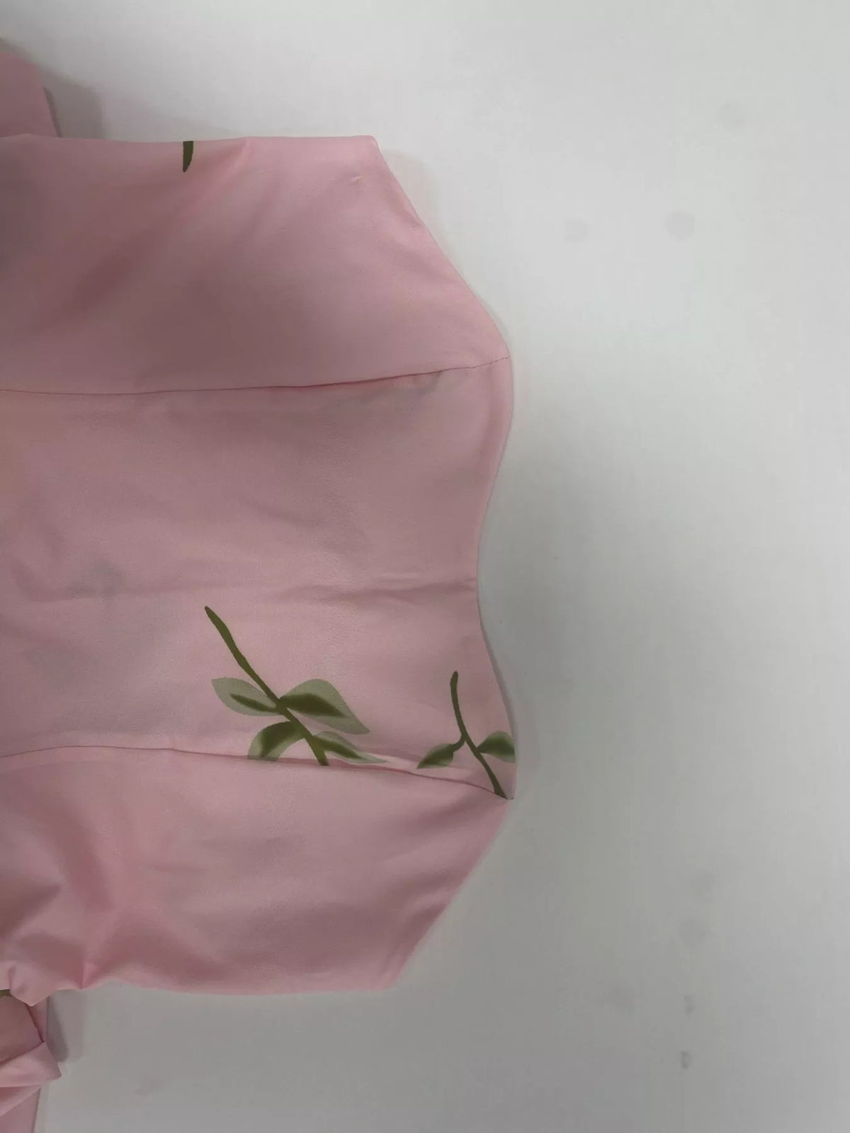 Close-up of pink dress fabric with small embroidered flower detail.