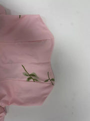 Close-up of pink dress fabric with small embroidered flower detail.