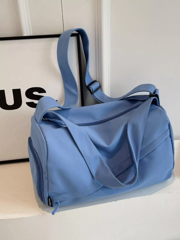 Blue duffel bag with two carry handles, adjustable shoulder strap and zipped side pocket, displayed on a shelf