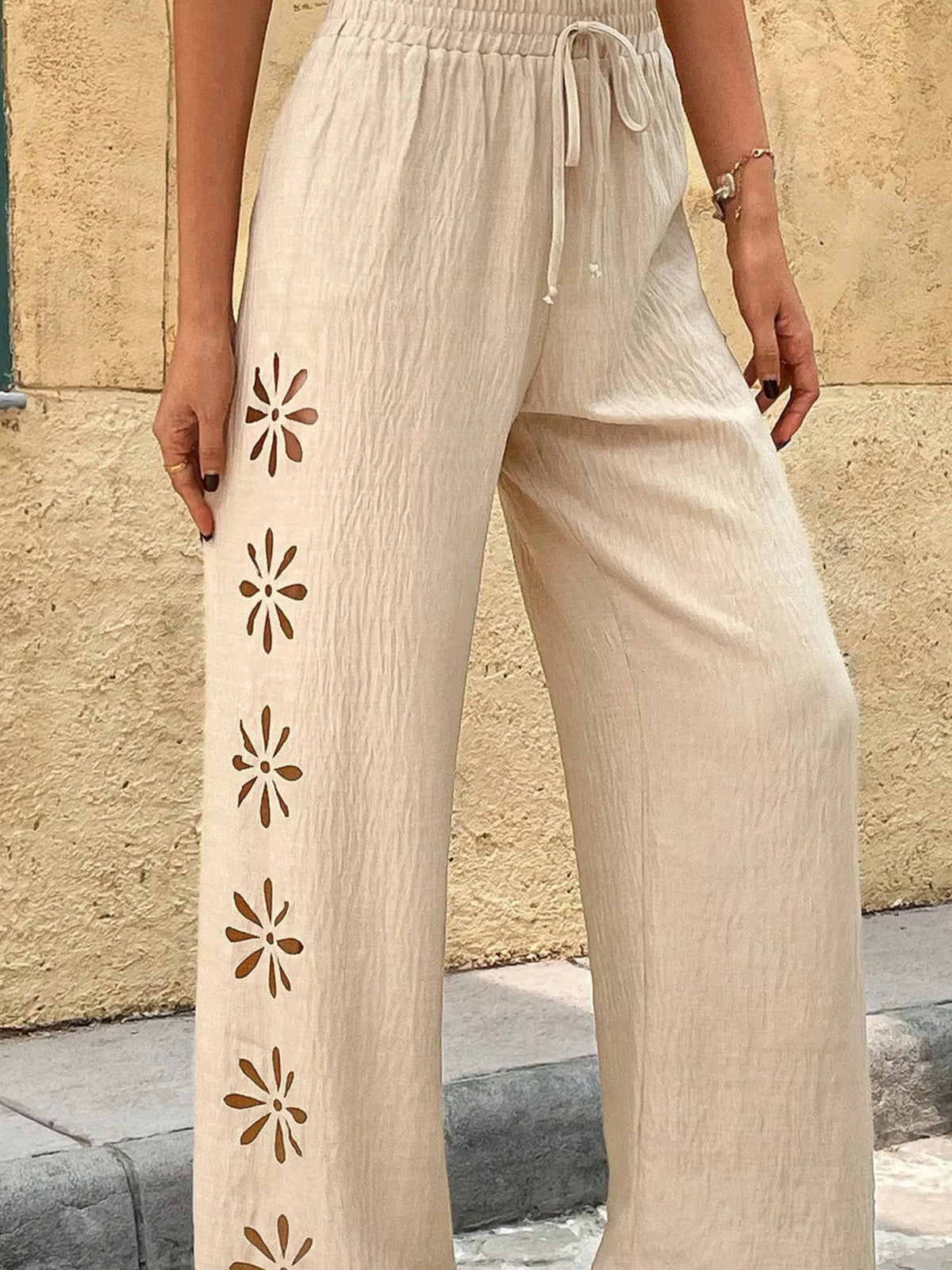 Model wearing cream embroidered wide-leg pants, front view