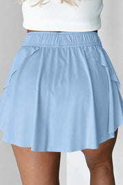 Back view of light blue skort with elastic waist and draped overlay.