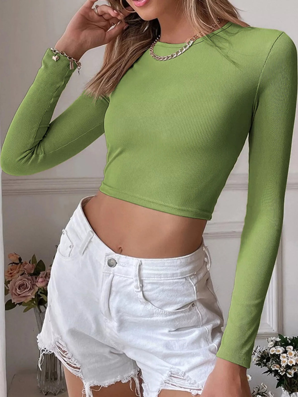 Model wearing a green ribbed long-sleeve crop top, front view
