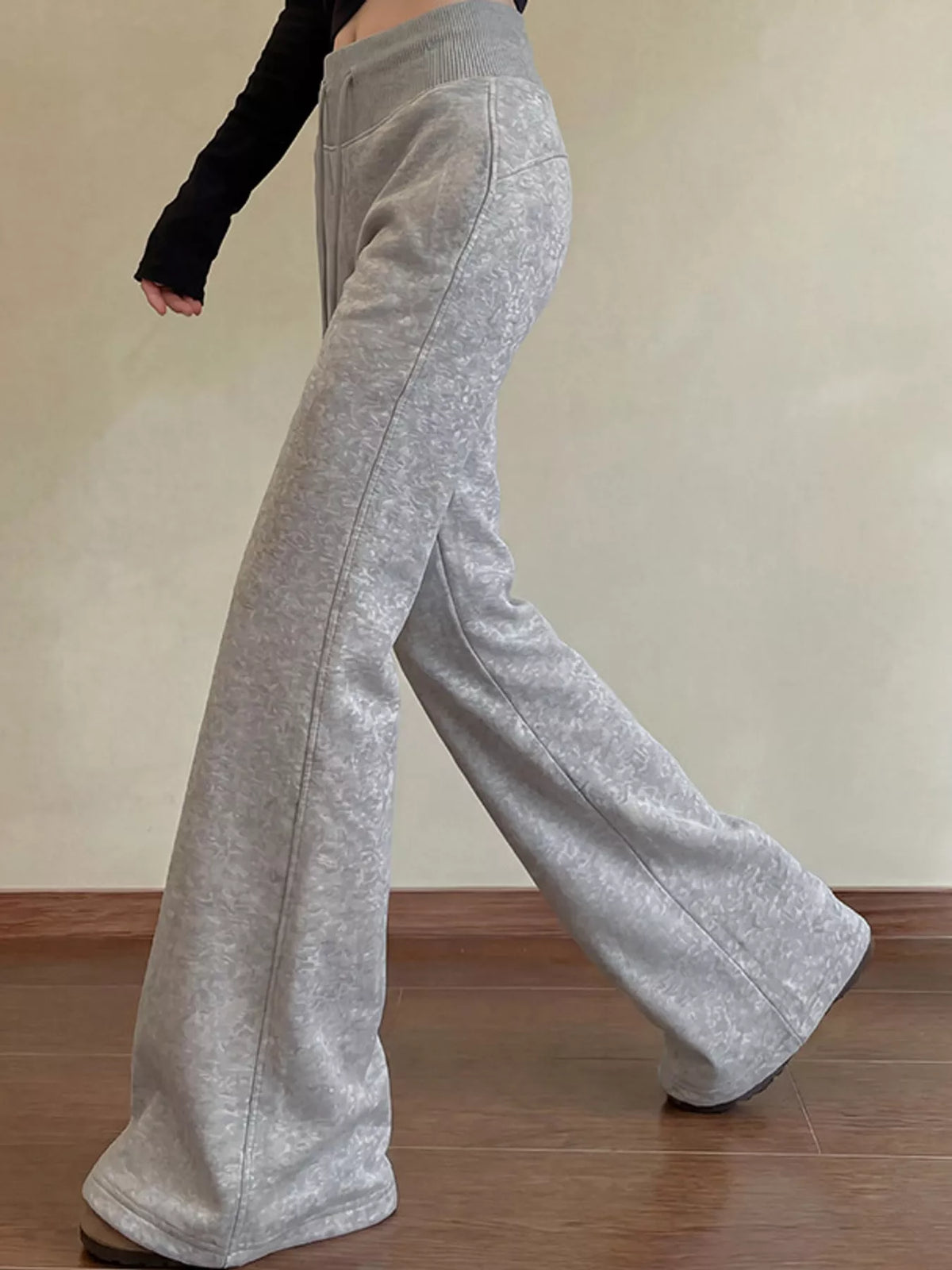 Grey high-waisted flare pants shown from the side while walking