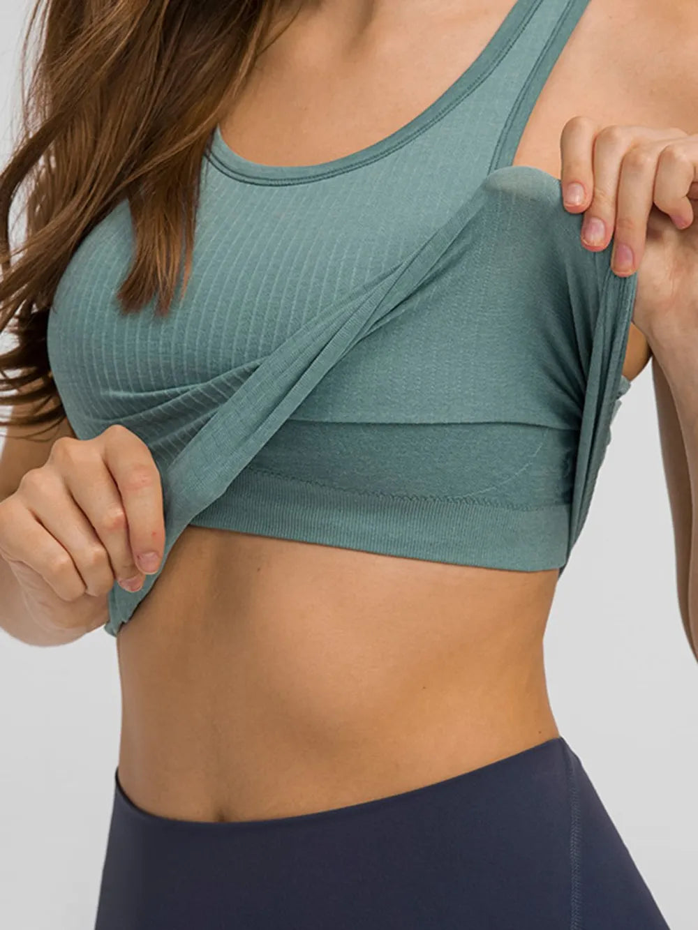 Close view of teal ribbed racerback tank lifted to show its built-in support band