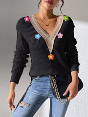 Black V-neck sweater with beige trim and colourful flower appliqués, standing view.