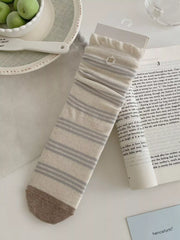 Cream sock with gray argyle band shown at mid-calf height