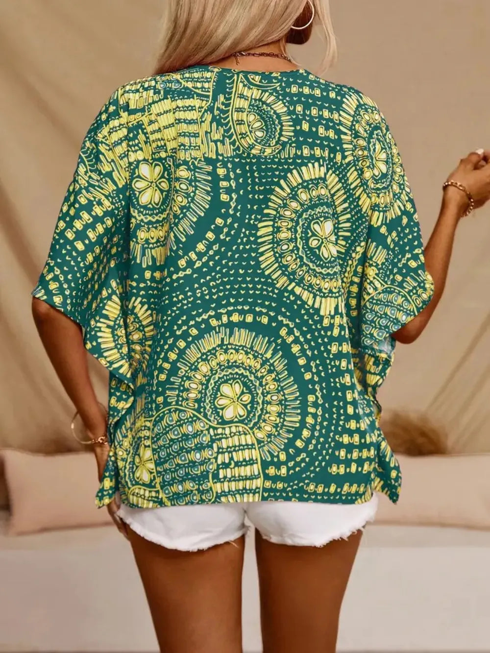 Back view of a green and yellow medallion-print blouse over white denim shorts.