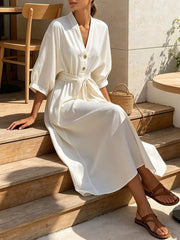 Model seated in white tie-waist button-front midi dress