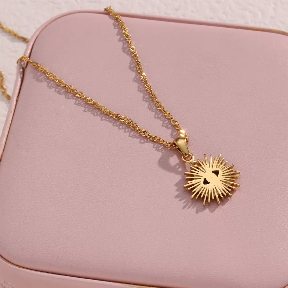 Gold-tone sunburst evil eye pendant on a pink jewelry case