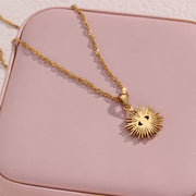 Gold-tone sunburst evil eye pendant on a pink jewelry case