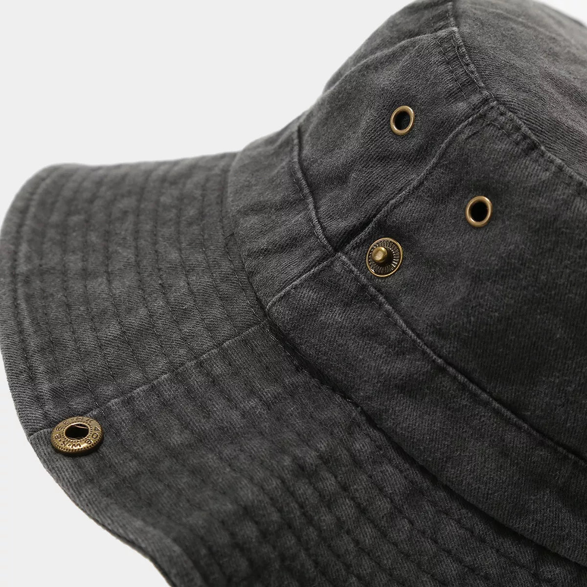 Close-up of metal ventilation eyelets and brim snaps on black hat