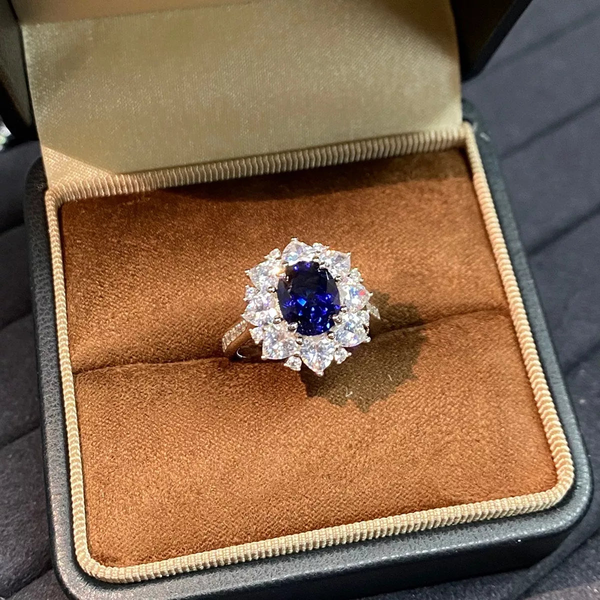 Royal-blue oval sapphire ring with clear halo stones shown in its presentation box