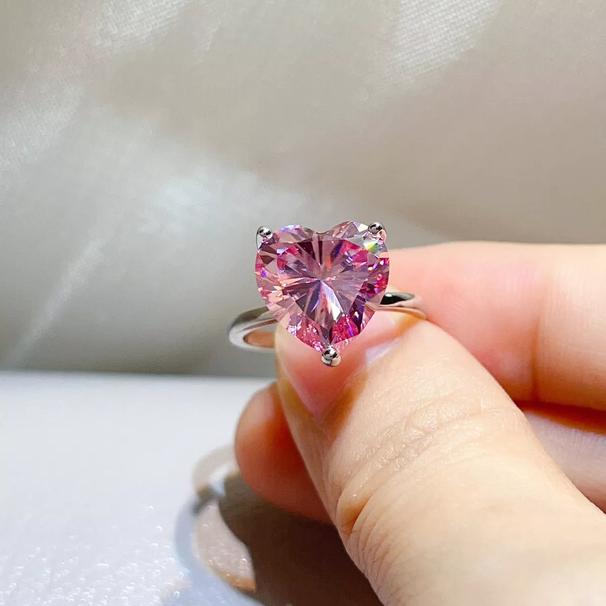 Close view of the pink heart-shaped centre stone and silver setting.