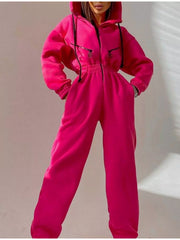 Women's bright pink hooded jumpsuit, model standing front view with hands at waist